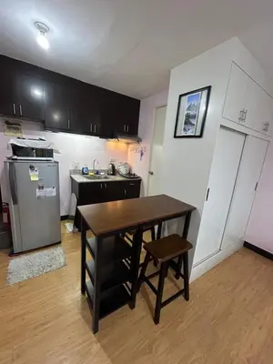 a small kitchen with a table and a refrigerator at Solstay in Manila