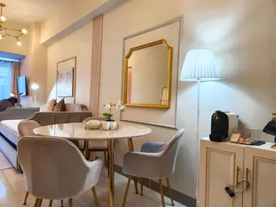 a living room with a table and chairs and a couch at LUXESTAYSMNL Parisian Charm 1BR Suite Pool Gym 400MBPS WiFi Netflix Amazing City View in Manila