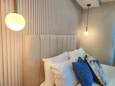 a bedroom with a bed with pillows and two lights at LUXESTAYSMNL Parisian Charm 1BR Suite Pool Gym 400MBPS WiFi Netflix Amazing City View in Manila