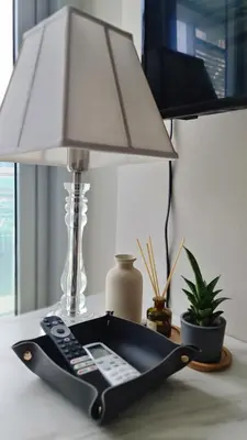 a table with a lamp and a remote control at LUXESTAYSMNL Parisian Charm 1BR Suite Pool Gym 400MBPS WiFi Netflix Amazing City View in Manila
