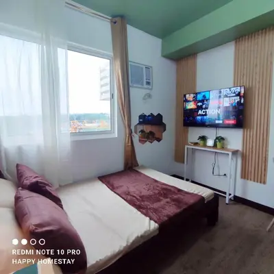 a bedroom with a bed and a large window at Happy Homestay at Fullerton Suites Condo near Nuvali and Tagaytay in Silang