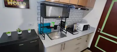 a kitchen with a sink and a tv on a counter at Happy Homestay at Fullerton Suites Condo near Nuvali and Tagaytay in Silang