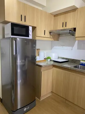 a kitchen with a stainless steel refrigerator and wooden cabinets at Brixton place near bgc in Manila