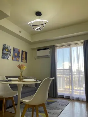 a dining room with a table and chairs and a window at Brixton place near bgc in Manila