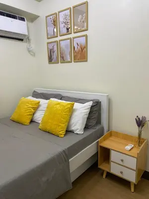 a bedroom with a bed with yellow pillows and a table at Brixton place near bgc in Manila