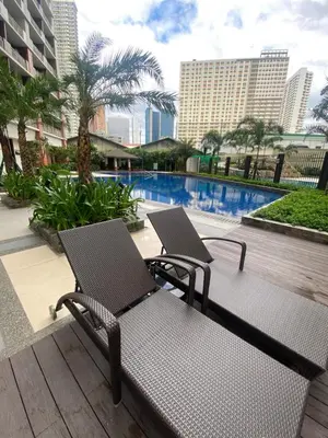 a couple of chairs sitting next to a swimming pool at Brixton place near bgc in Manila