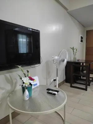 a living room with a tv and a table with flowers at LDN Studio Unit Two Palm Tree in Manila