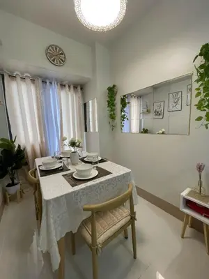 a dining room with a table and chairs and a clock at Molly Shore Getaway Unit 1276 in Manila