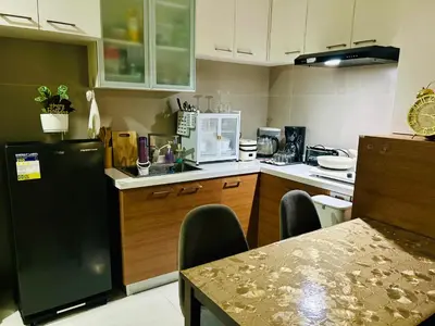 a kitchen with a table and a black refrigerator at Cozy 1BR with BGC View Gym and Pool Included in Manila