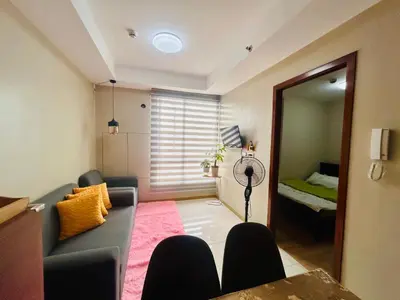 a living room with a couch and a mirror at Cozy 1BR with BGC View Gym and Pool Included in Manila