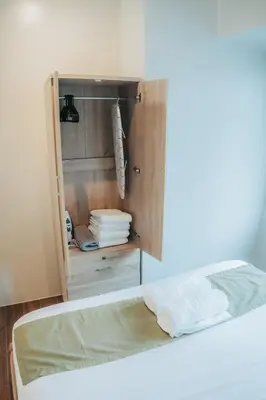 a room with a bed and a cabinet with towels at The House of Five - Brand New Hotel Style Condo in Manila