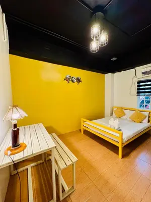 a yellow room with a bed and a table at Cheese Hostel Manila in Manila