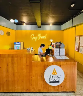 a woman sitting at a desk in a yellow room at Cheese Hostel Manila in Manila