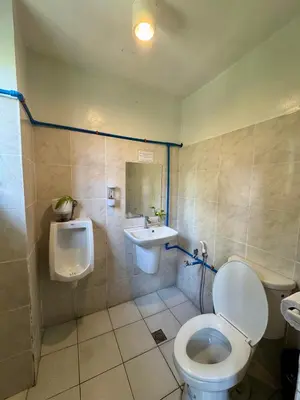 a bathroom with a toilet and a sink and a urinal at Cheese Hostel Manila in Manila