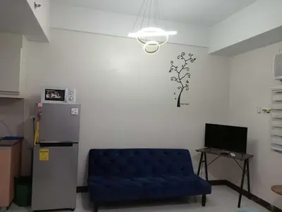 a living room with a blue couch and a refrigerator at Newport 101 - East Wing in Manila