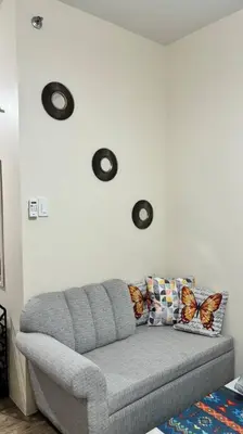 a living room with a gray couch with butterflies on the wall at Cozy Studio Condo Unit at Fullerton Suites in Silang