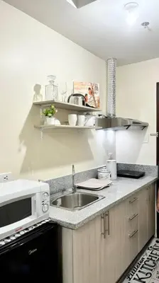 a kitchen with a sink and a microwave at Cozy Studio Condo Unit at Fullerton Suites in Silang