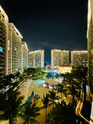 a city at night with palm trees and buildings at Azure Urban Beach Residences with PS4 near Airport in Manila
