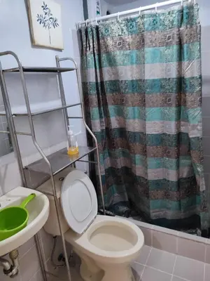 a bathroom with a toilet and a shower curtain at Royal loft with breakfast options in Cainta