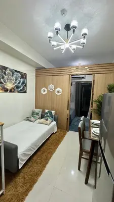 a bedroom with a bed and a chandelier at The GoodVibes Condotel Red Residences Makati in Manila