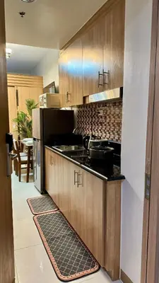 a kitchen with wooden cabinets and a stove top oven at The GoodVibes Condotel Red Residences Makati in Manila