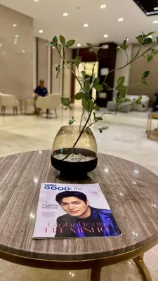 a vase with a plant on a table with a magazine at The GoodVibes Condotel Red Residences Makati in Manila