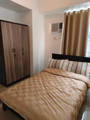 a bedroom with a bed and a wooden cabinet at Shore Res 2 Br 2Bath 1417 in Manila
