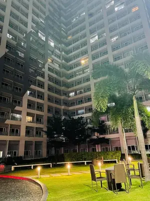 a large building with chairs in the grass in front of a building at SMDC Grace Residences in Manila