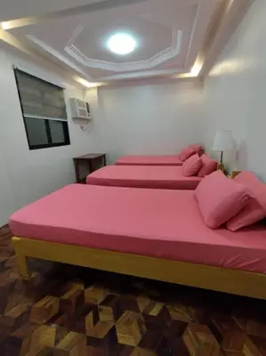 two beds in a room with pink sheets and pillows at 4-5br Apartment in Paranaque for Staycation in Manila