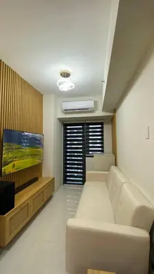 a living room with a white couch and a flat screen tv at Enchanted Gateway by Shore 3 in Manila