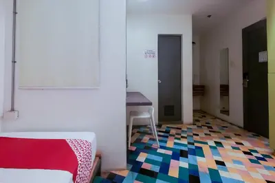 a room with a bed and a table and a colorful floor at Spot On Junction Hostel in Manila