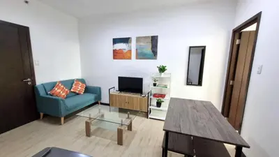 a living room with a blue couch and a table at Cozy 1 BR San Lorenzo Place Netflix 4KM NAIA in Manila