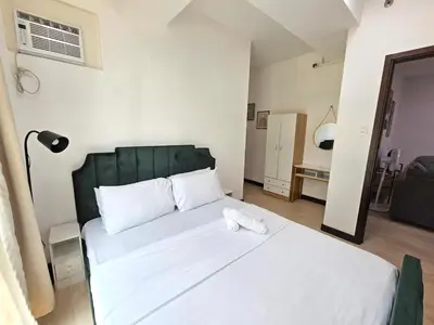 a bedroom with a large white bed with a green headboard at Cozy 2BR 2Bath San Lorenzo Place Netflix 4KM NAIA in Manila
