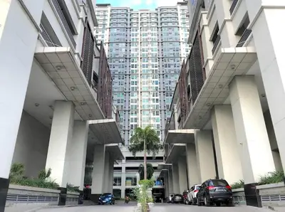 a large building with cars parked in a parking lot at Cozy 2BR 2Bath San Lorenzo Place Netflix 4KM NAIA in Manila