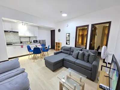 a living room with a couch and a kitchen at Cozy 2BR 2Bath San Lorenzo Place Netflix 4KM NAIA in Manila