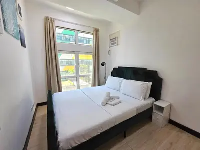 a bedroom with a bed with white sheets and a window at Cozy 2BR 2Bath San Lorenzo Place Netflix 4KM NAIA in Manila
