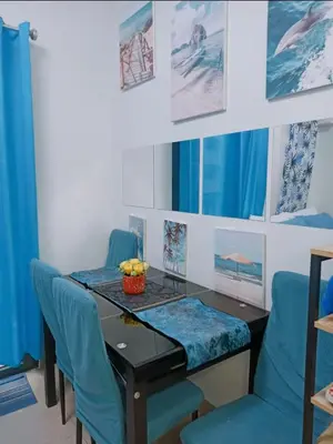 a dining room with a table and blue chairs at E & R Staycation Condotel near Mall of Asia in Manila