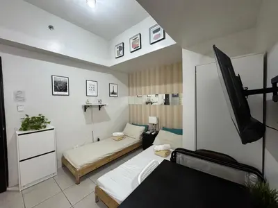 a room with two beds and a flat screen tv at AMA Tower Studio, 8th flr, near DMW and SM Megamall in Manila
