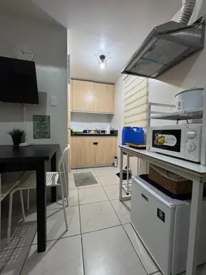 a kitchen with a table and a counter with a microwave at AMA Tower Studio, 8th flr, near DMW and SM Megamall in Manila