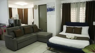 a bedroom with a couch and a bed and a chair at Experience Santa Rosa Comfort at MEGAN Montagne Suite in Santa Rosa