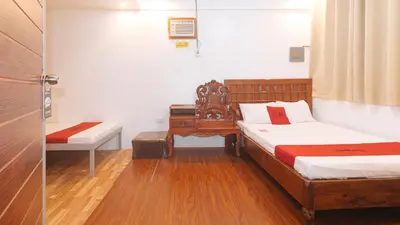 a bedroom with two beds and a bench and a table at RedDoorz at Prince Hotel near NAIA T1 in Manila