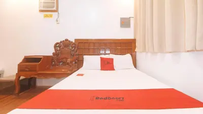 a bedroom with a bed with a chair and a piano at RedDoorz at Prince Hotel near NAIA T1 in Manila