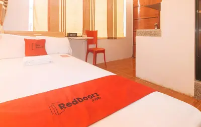 a bedroom with a bed with an orange blanket on it at RedDoorz at Prince Hotel near NAIA T1 in Manila