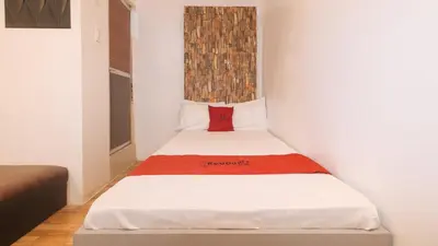 a small bedroom with a bed with a red pillow at RedDoorz at Prince Hotel near NAIA T1 in Manila