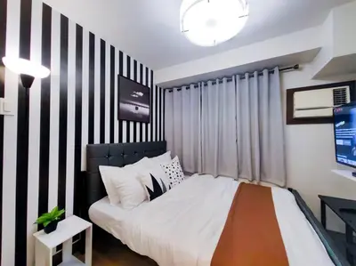 a bedroom with a bed with a black and white striped wall at 1BR Condotel Ridgewood Towers Taguig City #RW07 in Manila