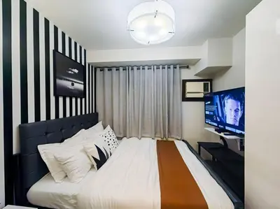 a bedroom with a large bed and a television at 1BR Condotel Ridgewood Towers Taguig City #RW07 in Manila