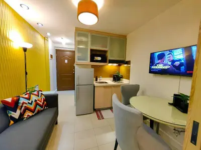 a living room with a table and a kitchen with a tv at 1BR Condotel Ridgewood Towers Taguig City #RW08 in Manila