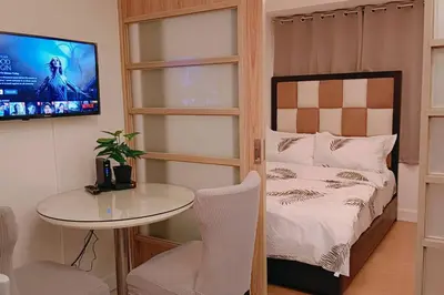 a bedroom with a bed and a table and a tv at 1BR Condotel Ridgewood Towers Taguig City #RW08 in Manila