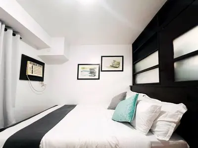 a bedroom with a large bed with two windows at 1BR Condotel Ridgewood Towers Taguig City #RW12 in Manila