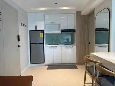 a kitchen with white cabinets and a black refrigerator at Dazzling fully furnished unit BGC w Pool in Manila